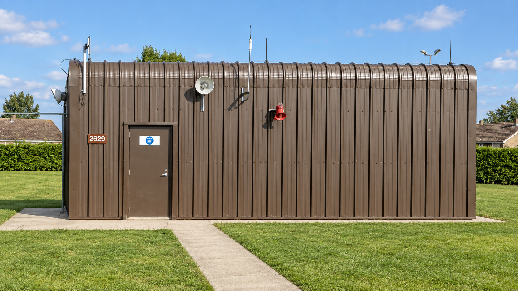 Brown steel-clad fuel-installation building with horns, lighting and aerials on a concrete apron at RAF Mildenhall
