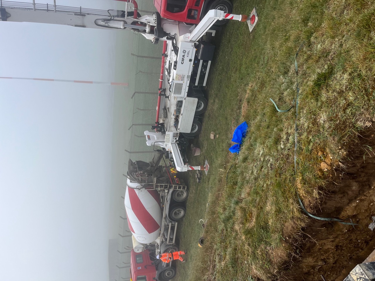 Concrete being placed beside airfield infrastructure in foggy conditions at RAF Fairford