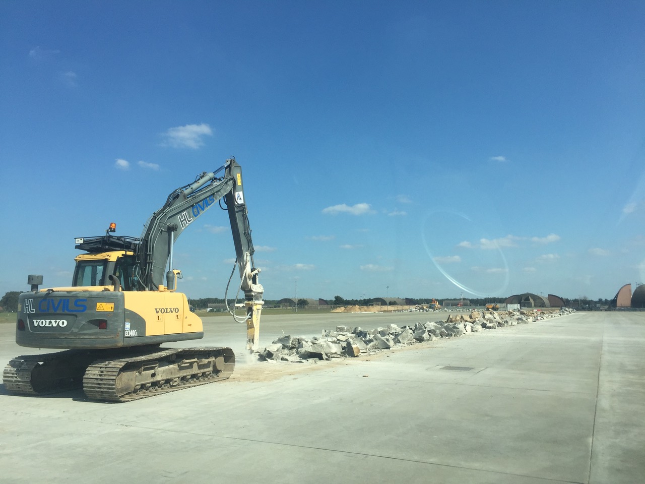 HL Civils excavator breaking out the existing concrete hardstanding at RAF Lakenheath under a clear sky