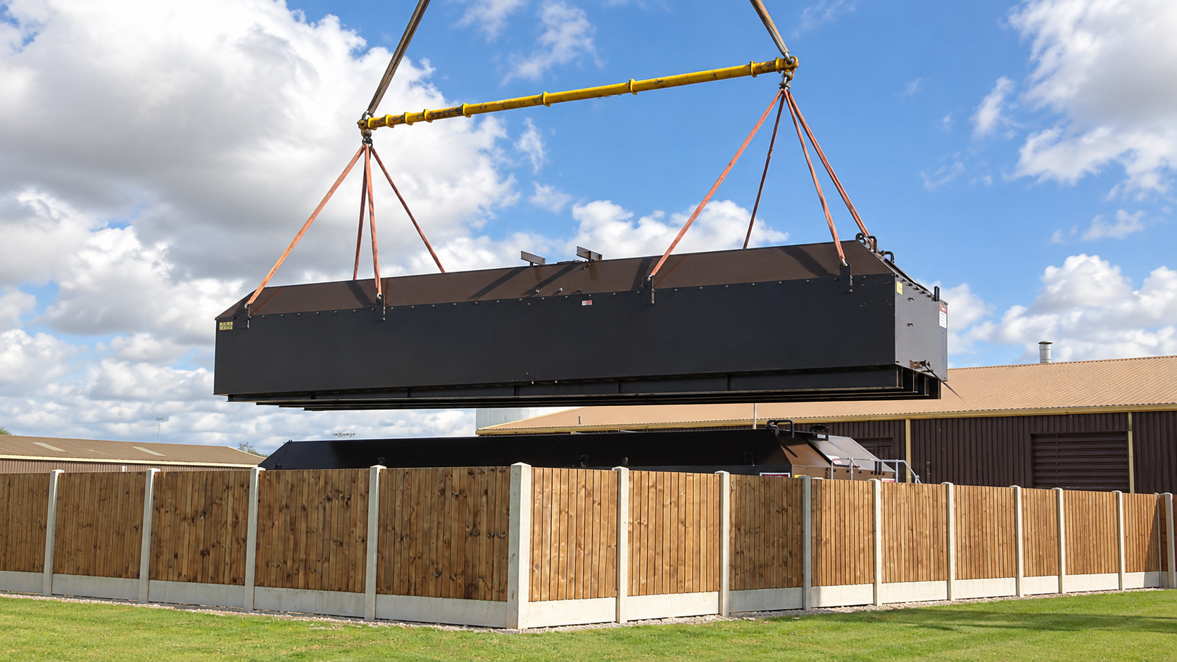 Crane lifting a large dark steel tank section into position at RAF Fairford