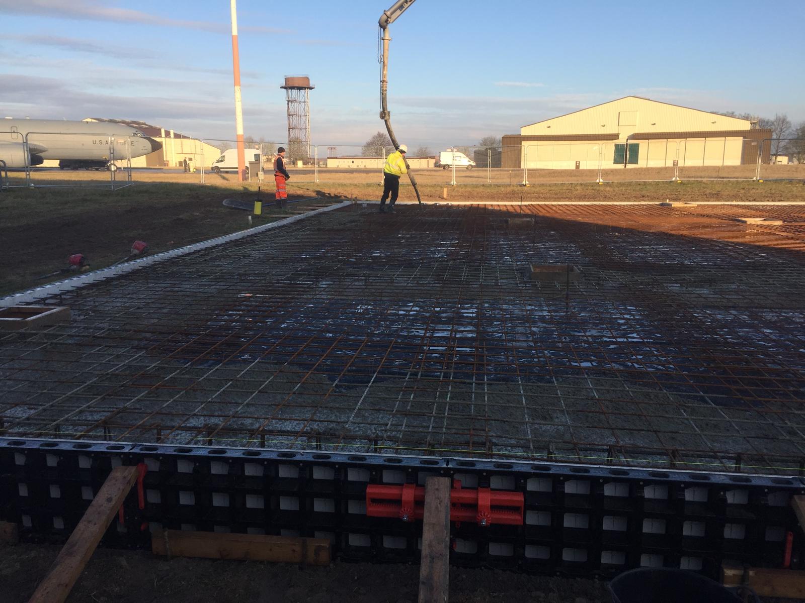 Concrete being poured by pump over reinforcement mesh for the new hardstanding at RAF Mildenhall